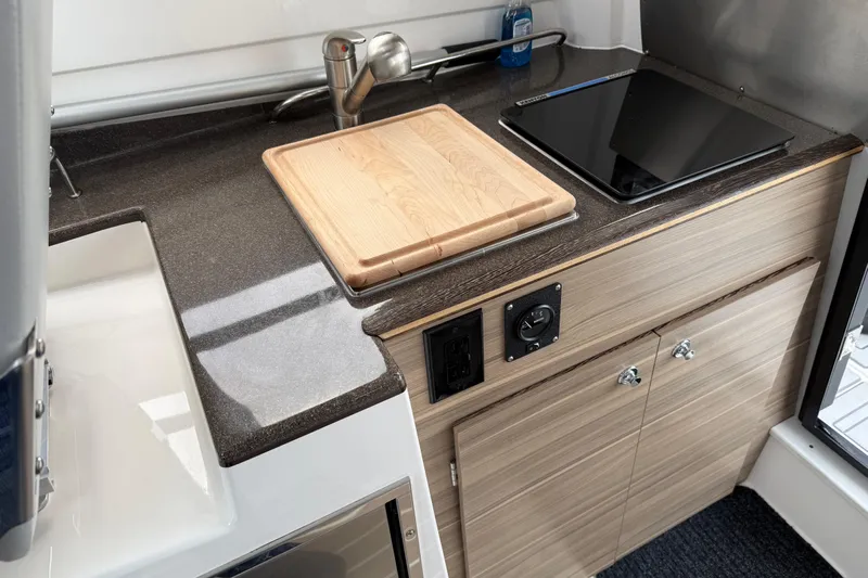  Yacht Photos Pics Compact kitchen area in 2024 Solara S-250 Coupe with sink, cutting board, and stove.