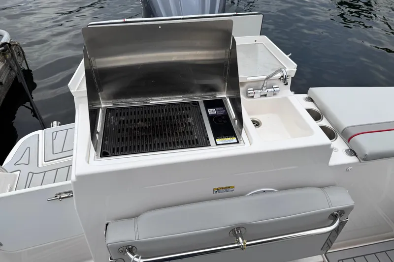  Yacht Photos Pics Outdoor grill and sink on 2024 Solara S-250 Coupe boat, docked by the water.