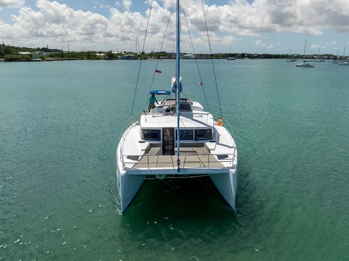 Cat Tales Yacht Photos Pics Bali 4.2 catamaran, 2022 model, anchored in clear turquoise waters under a partly cloudy sky.