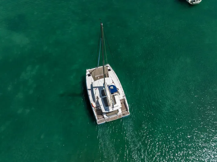 Cat Tales Yacht Photos Pics Aerial view of a 2022 Bali 4.2 catamaran sailing on clear turquoise water.