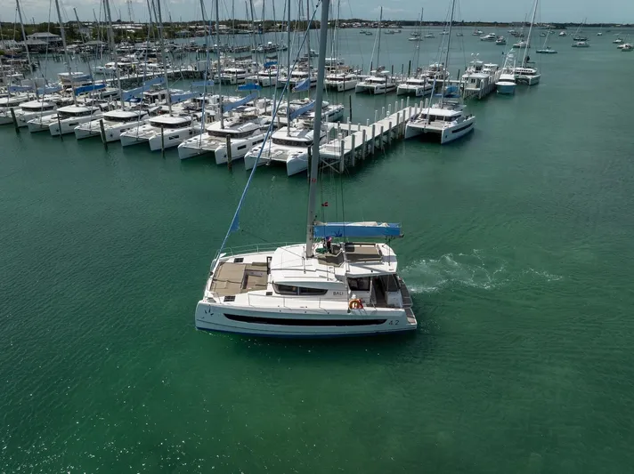 Cat Tales Yacht Photos Pics 2022 Bali 4.2 catamaran sailing in a marina with multiple docked boats.