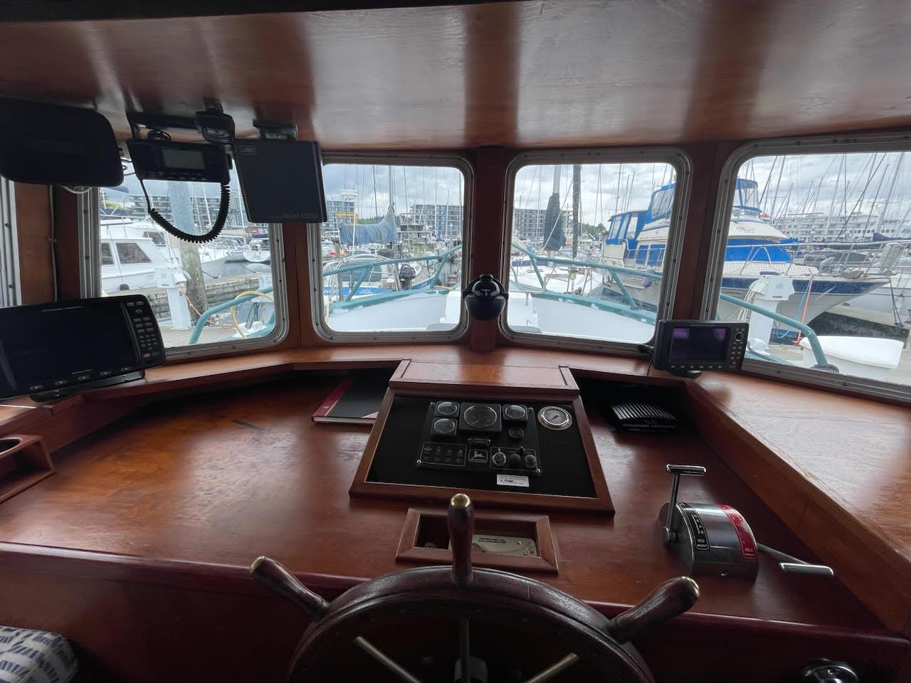 Pilot cabin of a 2010 Custom Trawler with navigation equipment and marina view.