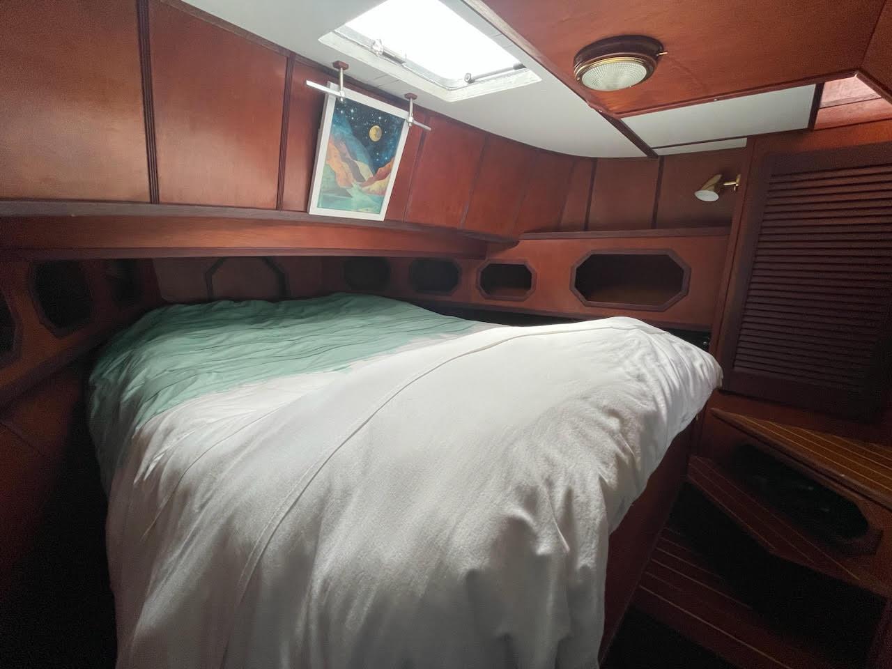 Cozy cabin interior of a 2010 custom trawler with a bed and wooden paneling.