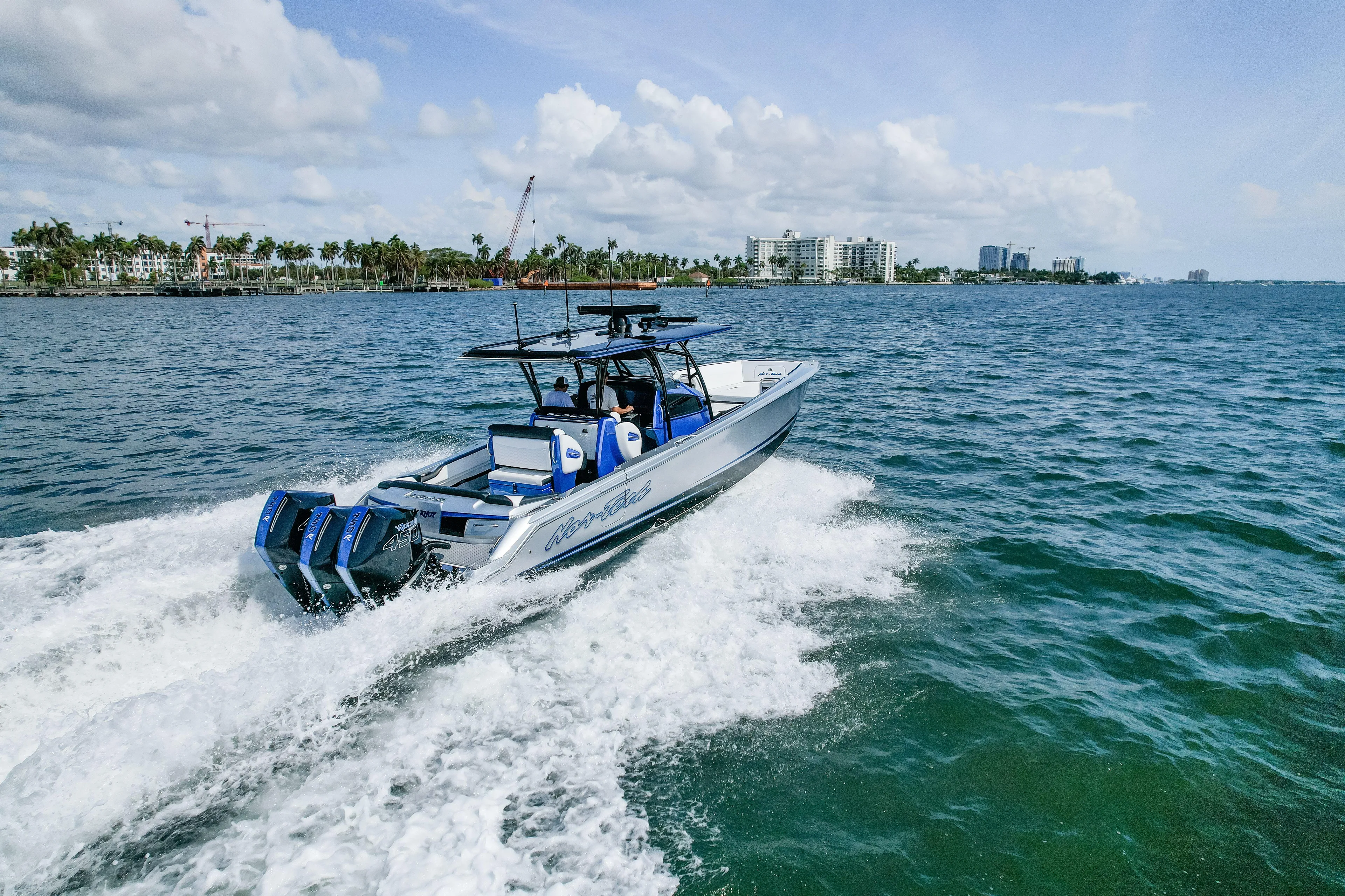  Yacht Photos Pics 2022 Nor-Tech 390 Center Console boat cruising on open water, cityscape in background.