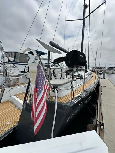 Edwina Yacht Photos Pics 2018 Jeanneau 54 yacht docked with American flag, featuring sleek design and wooden deck.
