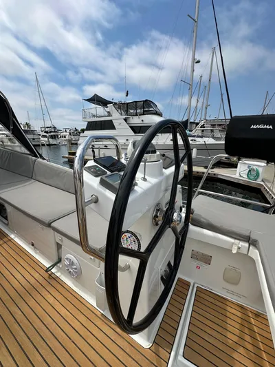 Edwina Yacht Photos Pics Steering wheel of a 2018 Jeanneau 54 yacht docked at a marina under blue skies.