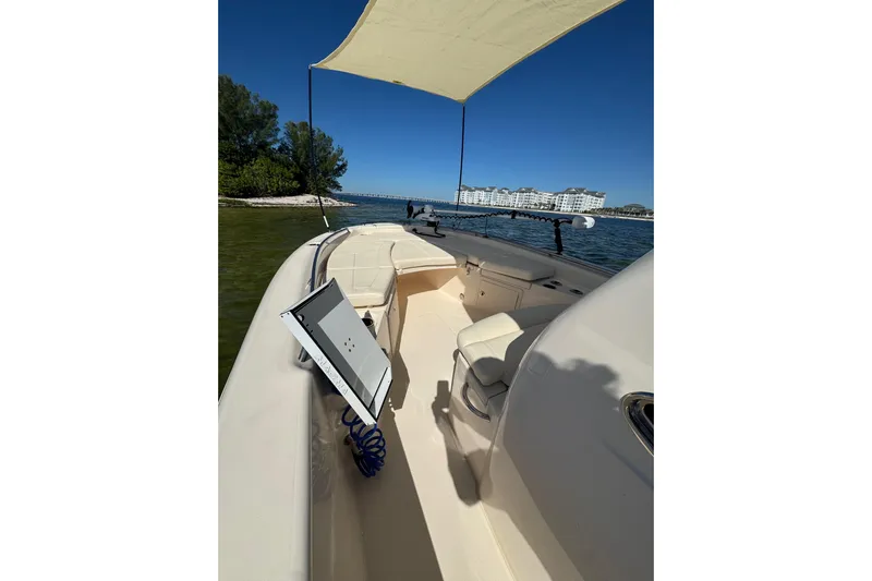  Yacht Photos Pics 2023 Grady-White 251 Coastal Explorer boat with canopy, on calm waters near shoreline.