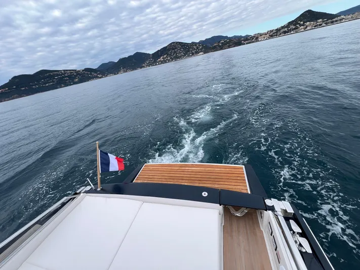 Stanislas Michel Yacht Photos Pics Itama 45 RS yacht cruising on open water, French flag, scenic coastal backdrop.