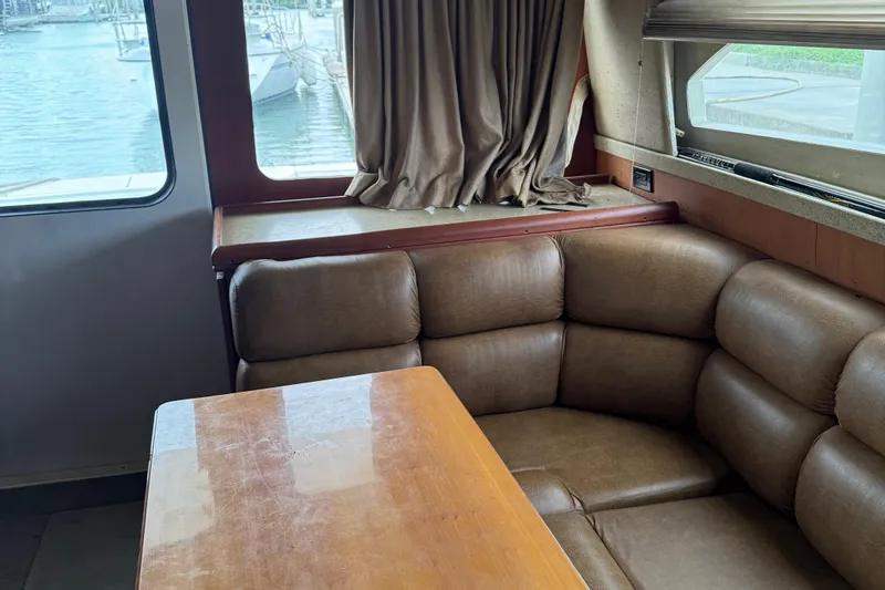  Yacht Photos Pics 2004 Luhrs 36 Convertible interior with brown leather seating and wooden table by a window.