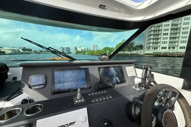 Abeona Yacht Photos Pics 2018 Axopar 37 Sport Cabin dashboard with navigation screens, steering wheel, and waterfront view.