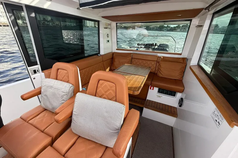 Abeona Yacht Photos Pics 2018 Axopar 37 Sport Cabin interior with brown leather seating and wooden accents.