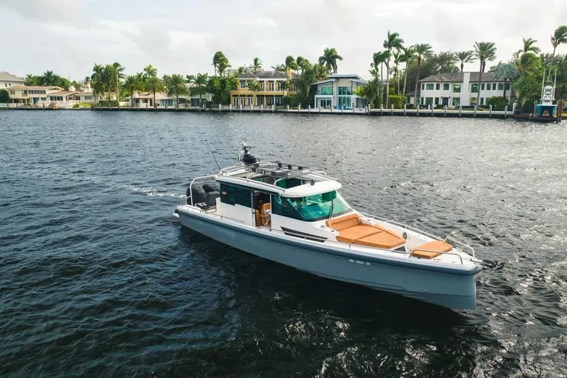 Abeona Yacht Photos Pics 2018 Axopar 37 Sport Cabin cruising on a scenic waterfront with luxury homes.