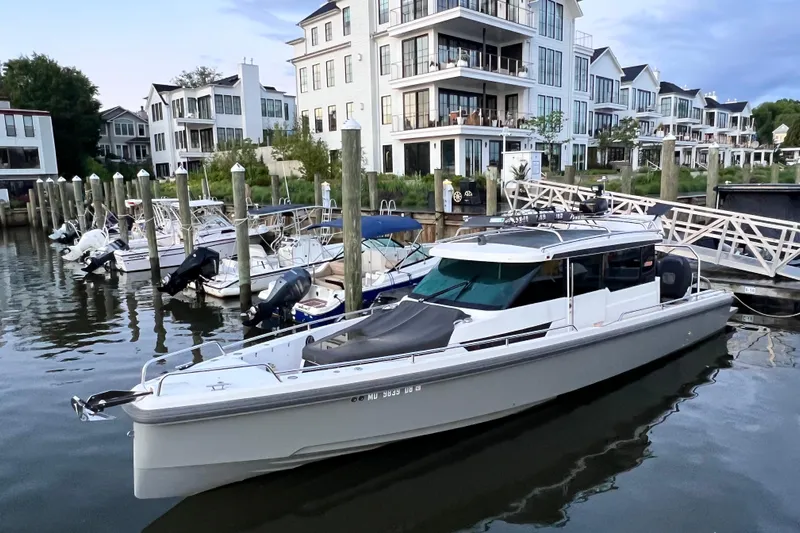 Abeona Yacht Photos Pics 2018 Axopar 37 Sport Cabin docked near modern waterfront buildings.