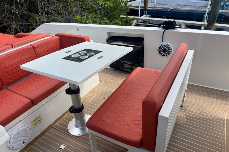  Yacht Photos Pics 2022 De Antonio Yachts D42 Open with red seating and a white table on deck.