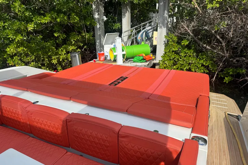  Yacht Photos Pics 2022 De Antonio Yachts D42 Open with vibrant red seating, docked near lush greenery.