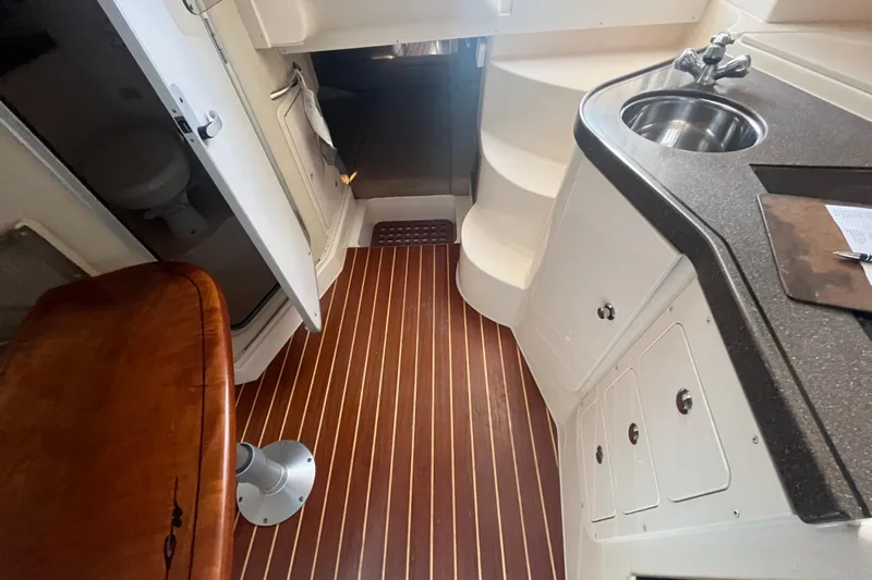 Revelry Yacht Photos Pics 2003 Grady-White Express 330 cabin interior with wood flooring and compact kitchenette.