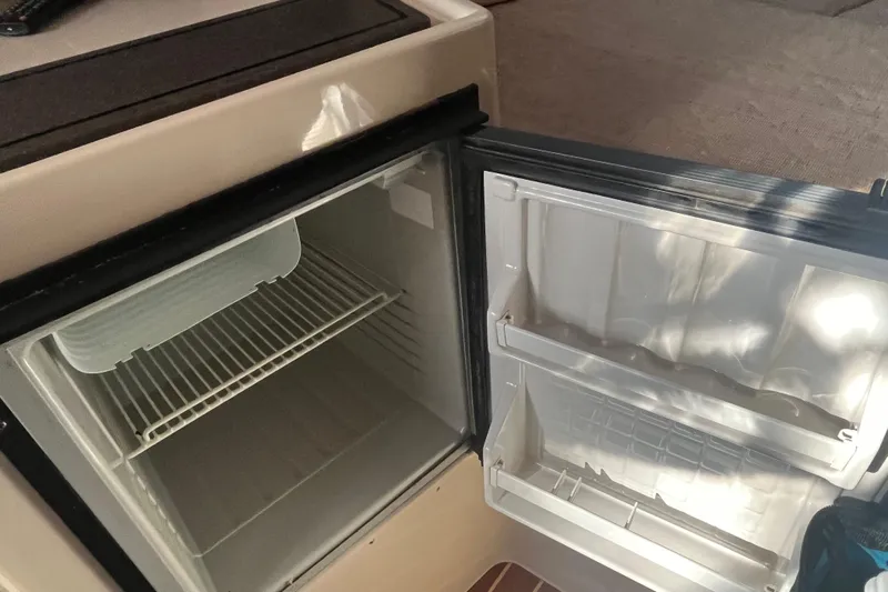 Revelry Yacht Photos Pics Open refrigerator inside 2003 Grady-White Express 330 boat, showing empty shelves and door compartments.