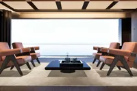 Modern living room with leather chairs, sleek table, and ocean view, 2026 design.