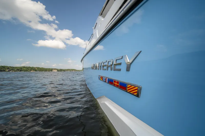  Yacht Photos Pics 2024 Monterey 385SS boat on water, showcasing sleek blue design and logo.
