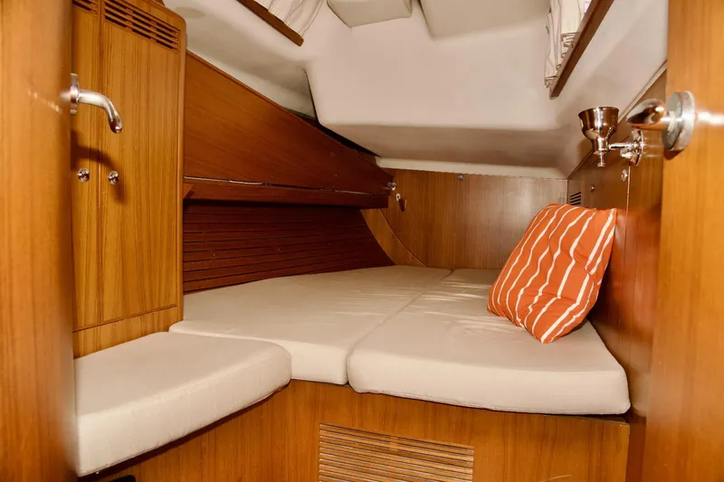  Yacht Photos Pics Cozy cabin interior of 2005 X-Yachts X-562 with wooden finish and striped pillow.