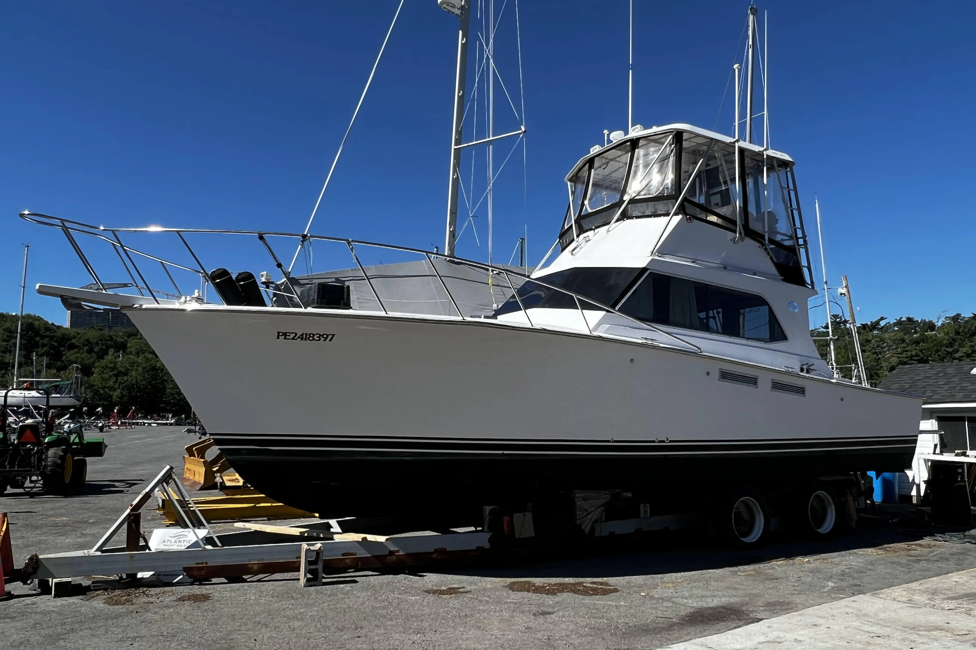 1988 Pace 40 Sport Fisherman boat on trailer at marina under clear blue sky.