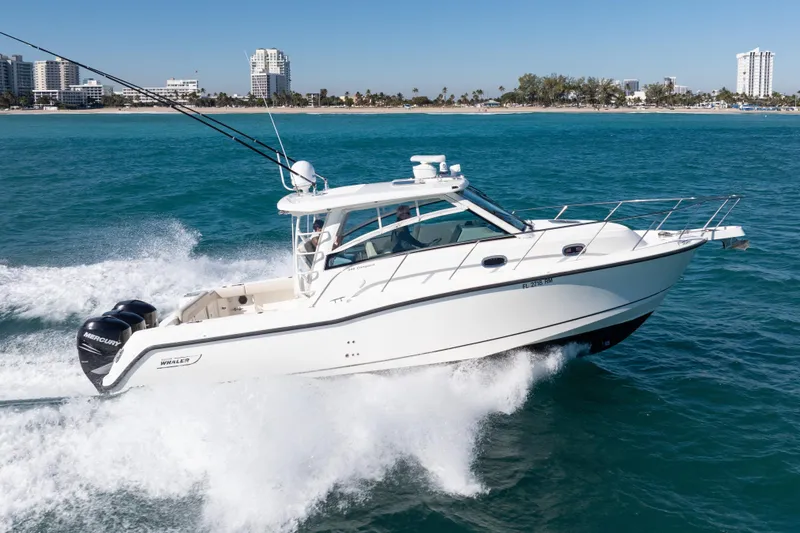  Yacht Photos Pics 2015 Boston Whaler 345 Conquest cruising on blue ocean near city skyline.