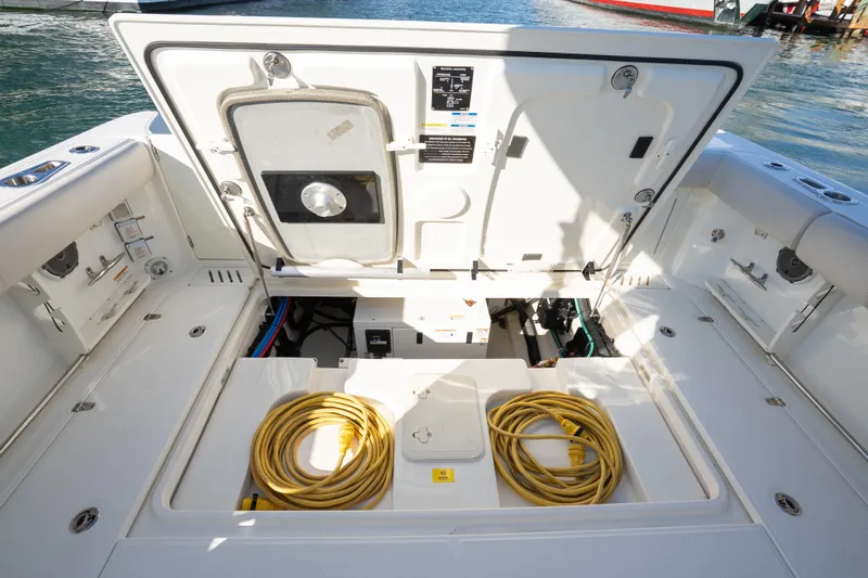  Yacht Photos Pics 2015 Boston Whaler 345 Conquest boat deck with open storage compartment and yellow cables.