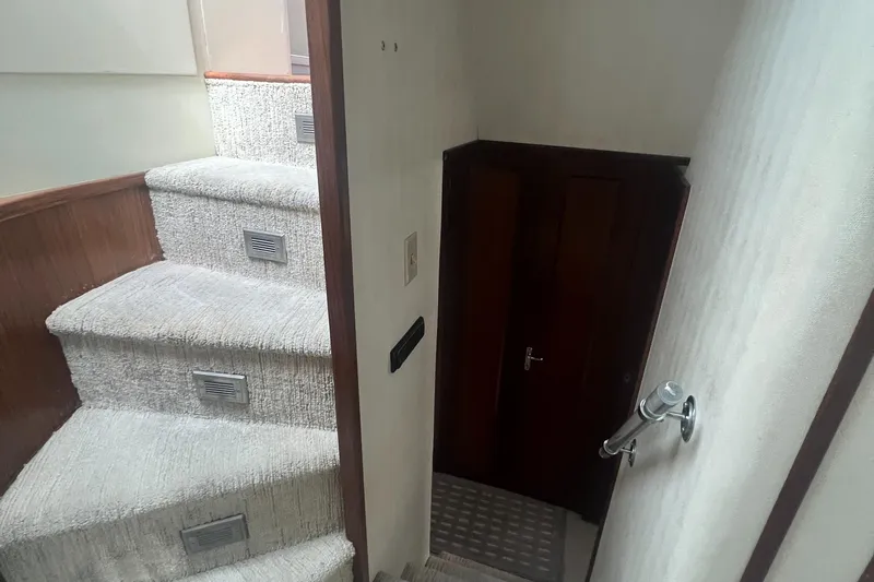 Havana Moon Yacht Photos Pics Interior stairs of 1990 Hatteras 70 Cockpit Motor Yacht, featuring carpeted steps and wooden accents.