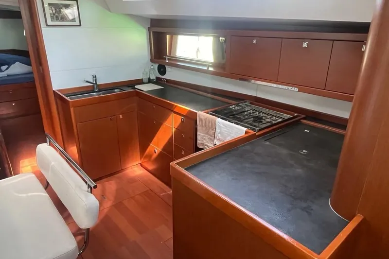  Yacht Photos Pics Interior of 2018 Beneteau Oceanis 48 yacht kitchen with wood cabinetry and modern appliances.