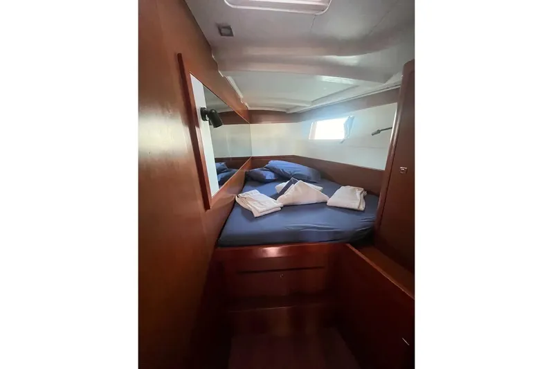  Yacht Photos Pics Cozy cabin interior of 2018 Beneteau Oceanis 48 yacht with blue bedding and wooden finish.