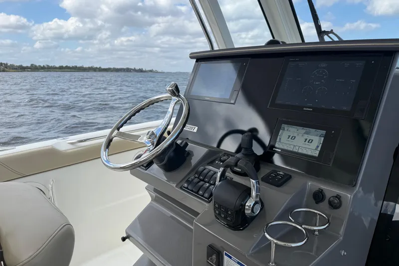  Yacht Photos Pics 2019 Pursuit S 328 Sport boat dashboard with steering wheel and navigation screens.