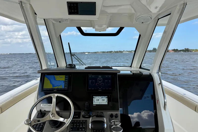  Yacht Photos Pics 2019 Pursuit S 328 Sport boat cockpit with navigation screens and steering wheel on open water.