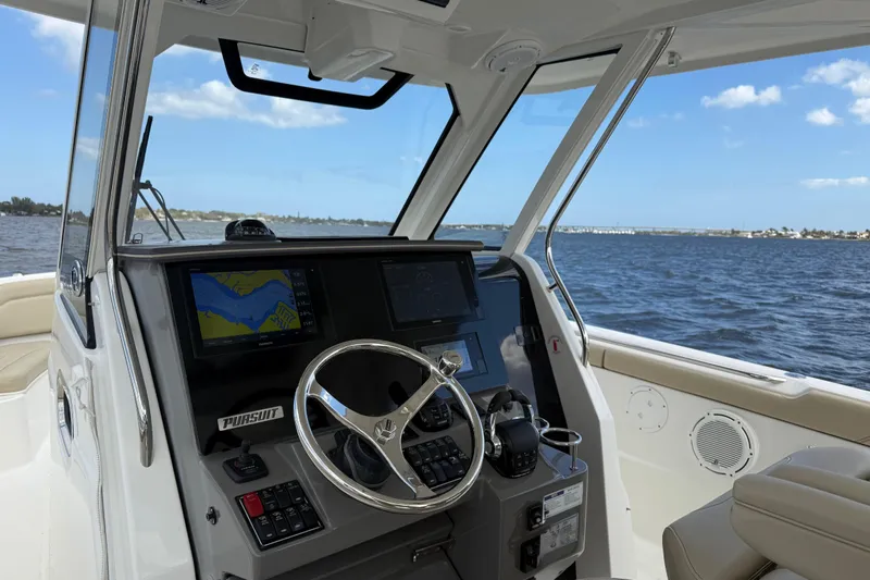  Yacht Photos Pics 2019 Pursuit S 328 Sport boat cockpit with navigation screens and steering wheel on open water.