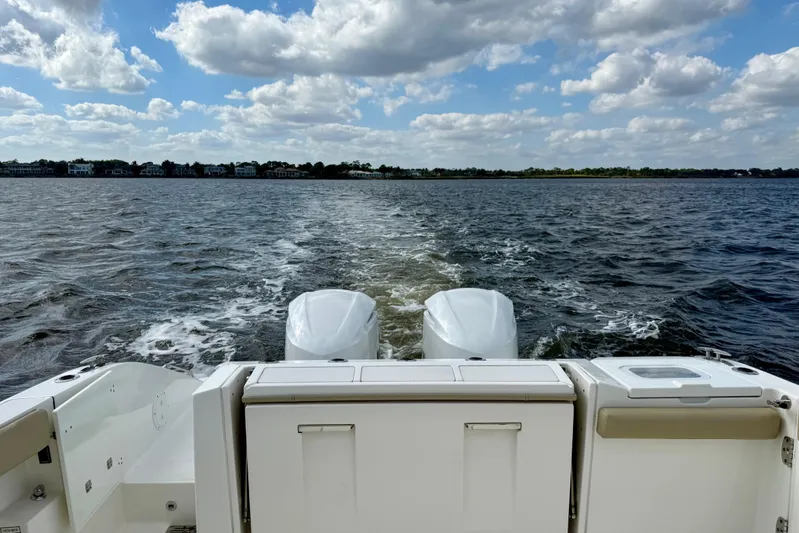  Yacht Photos Pics 2019 Pursuit S 328 Sport boat cruising on open water under a cloudy sky.