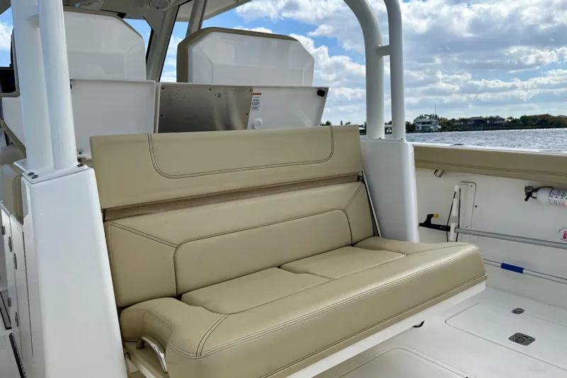  Yacht Photos Pics 2019 Pursuit S 328 Sport boat with beige seating, on a sunny day by the water.