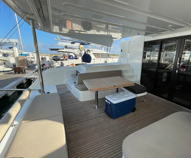 Kowi Kai Yacht Photos Pics 2020 Lagoon 50 catamaran deck with seating, table, and cooler at marina.