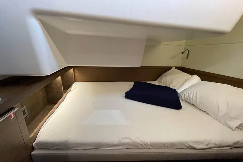 Kowi Kai Yacht Photos Pics 2020 Lagoon 50 yacht cabin with cozy bed, white linens, and wooden accents.