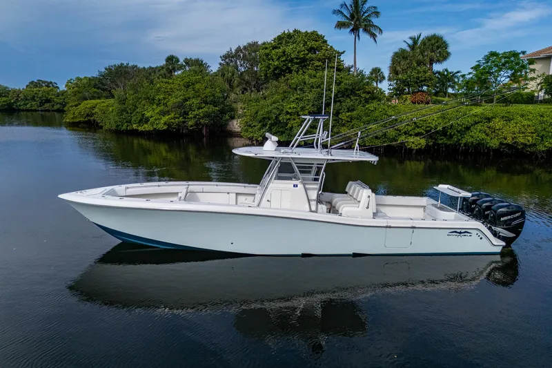  Yacht Photos Pics 2016 Invincible 39 Open Fisherman boat on calm water, surrounded by lush greenery.