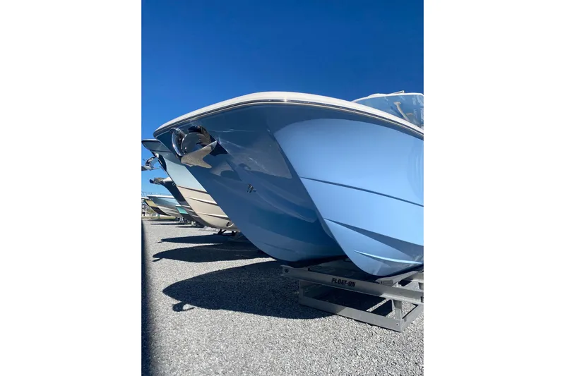  Yacht Photos Pics 2023 Invincible 33 Catamaran with sleek blue hull on trailer, under clear sky.