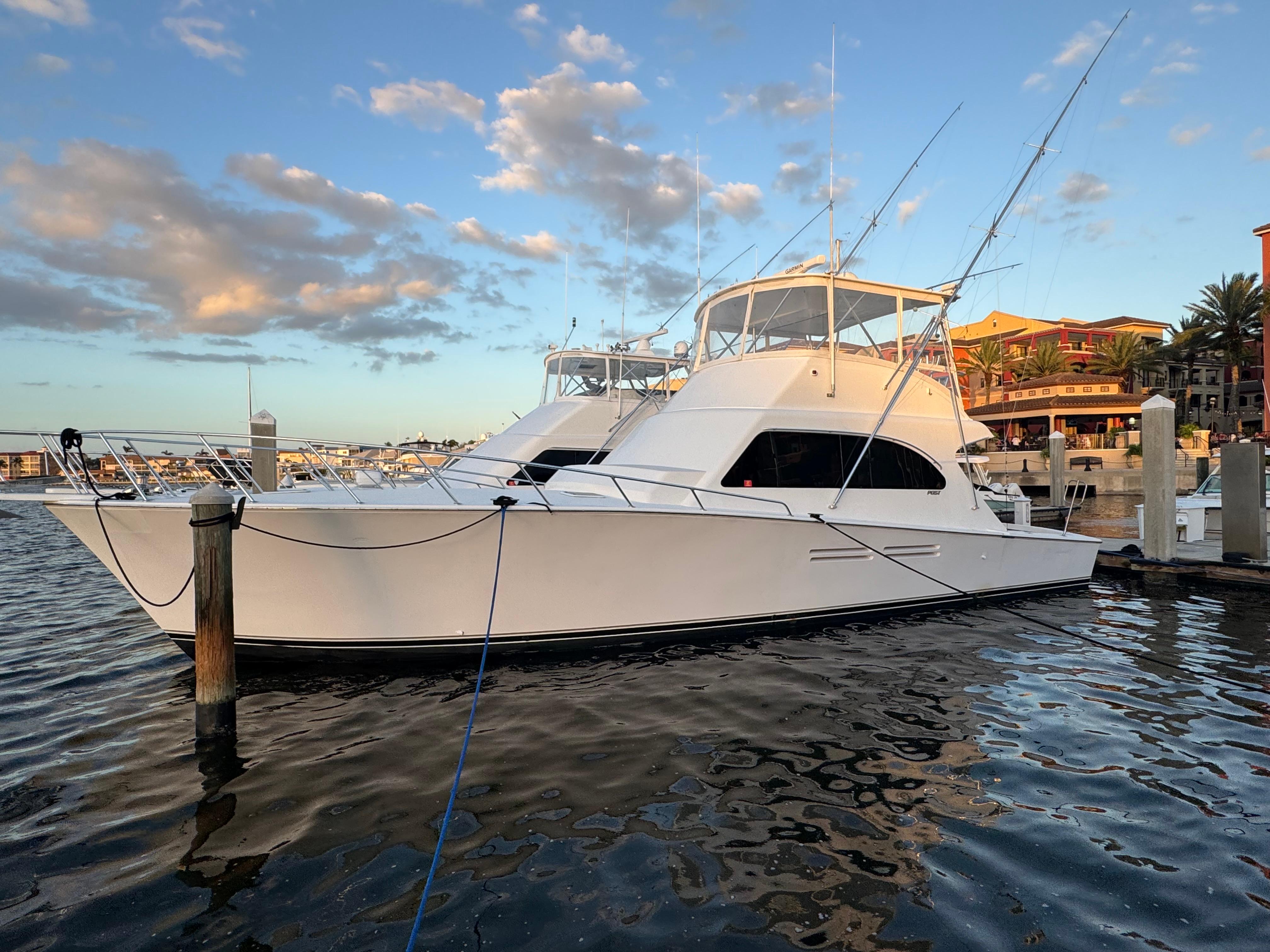 1999 Post 50 Convertible yacht docked at marina under blue sky.