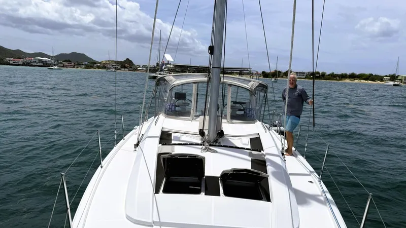 Batesea Yacht Photos Pics 2020 Beneteau Oceanis 46.1 sailboat on water with person on deck, cloudy sky.