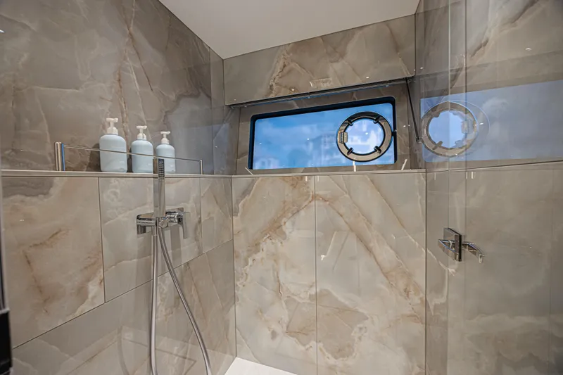 Hideout Yacht Photos Pics Luxurious bathroom in 2025 Sunseeker 88 Yacht with marble tiles and porthole window.