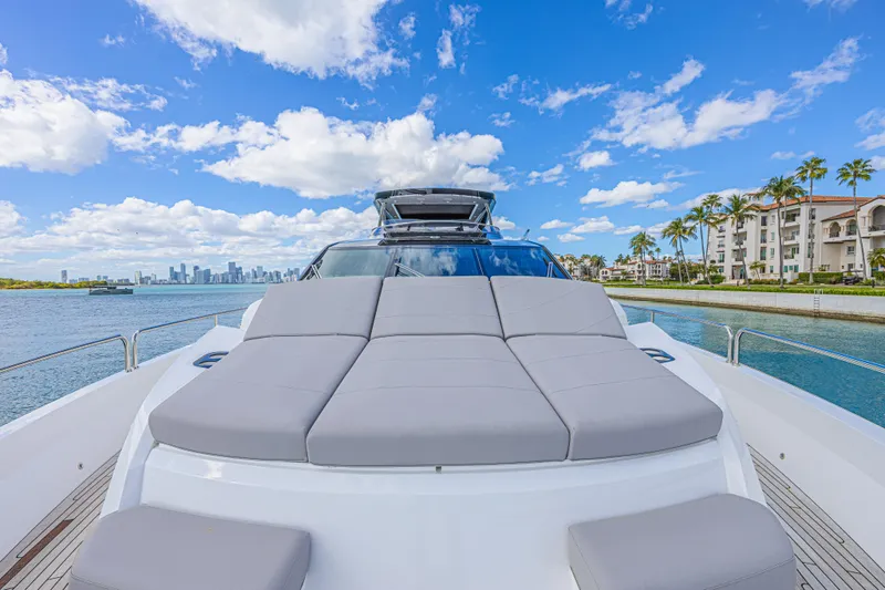 Hideout Yacht Photos Pics 2025 Sunseeker 88 Yacht with luxurious sunbed, city skyline, and waterfront view.