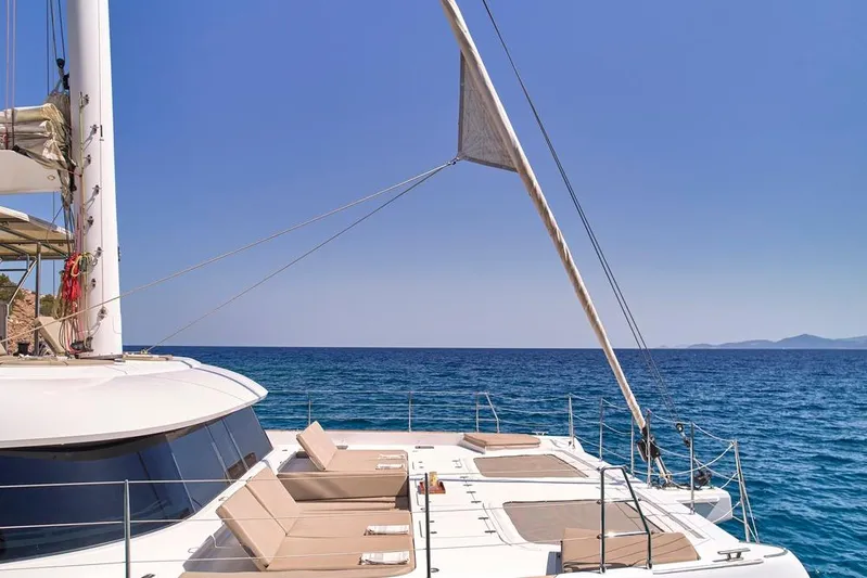 Adara Yacht Photos Pics Luxurious 2020 Sunreef 50 yacht with sunbeds, sailing on a clear blue sea.