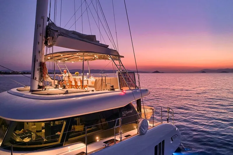 Adara Yacht Photos Pics Luxurious 2020 Sunreef 50 yacht at sunset, featuring elegant deck dining setup.