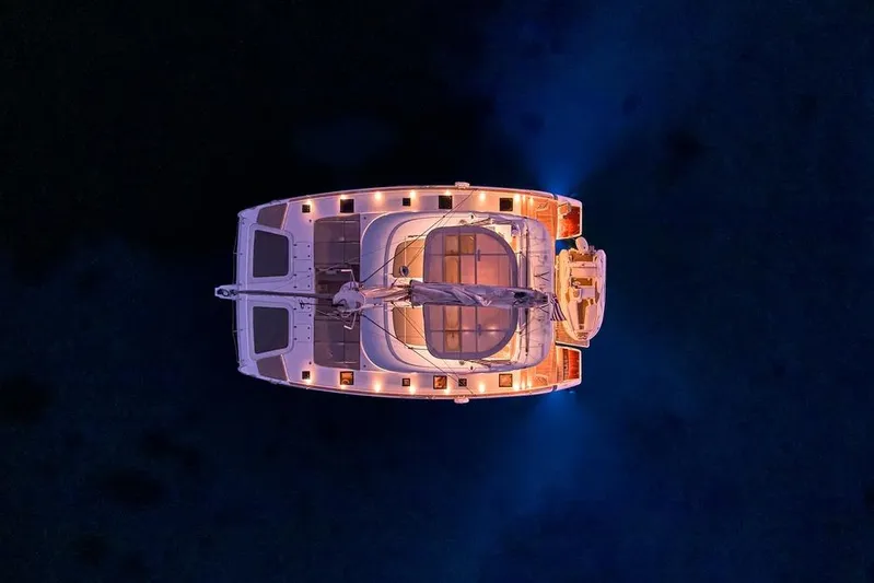 Adara Yacht Photos Pics Aerial view of illuminated 2020 Sunreef 50 yacht at night on dark water.