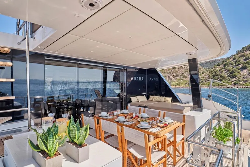 Adara Yacht Photos Pics Luxurious Sunreef 50 yacht deck with dining area, plants, and scenic ocean view, 2020 model.