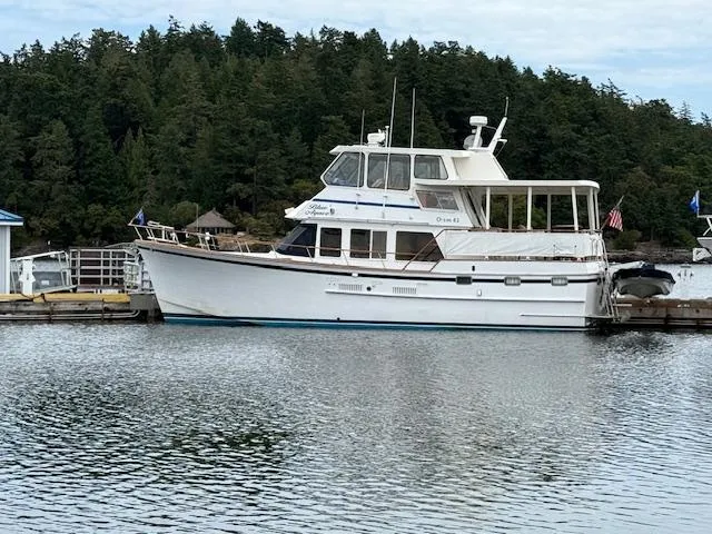 Blue Agave Yacht Photos Pics 1983 Ocean Alexander 43 Flush Aft Deck yacht docked by a forested shoreline.