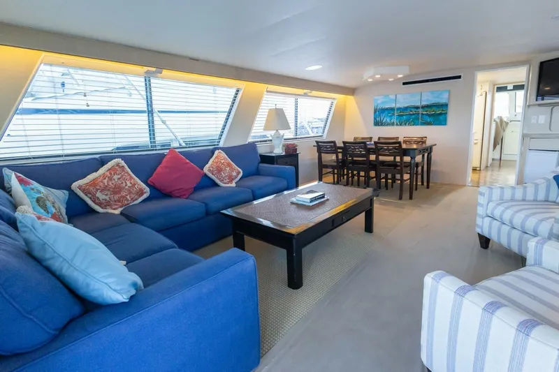 Yacht Photos Pics Luxurious interior of 1987 Hatteras 70 Cockpit Motor Yacht with blue sofa and dining area.