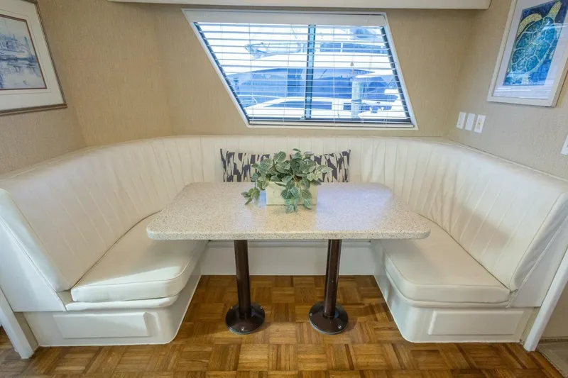  Yacht Photos Pics Elegant dining nook in 1987 Hatteras 70 Cockpit Motor Yacht with white seating and window view.